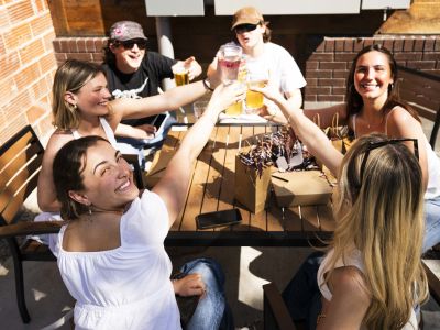 Image of new grads at Grad Fest doing a cheers with their drinks.