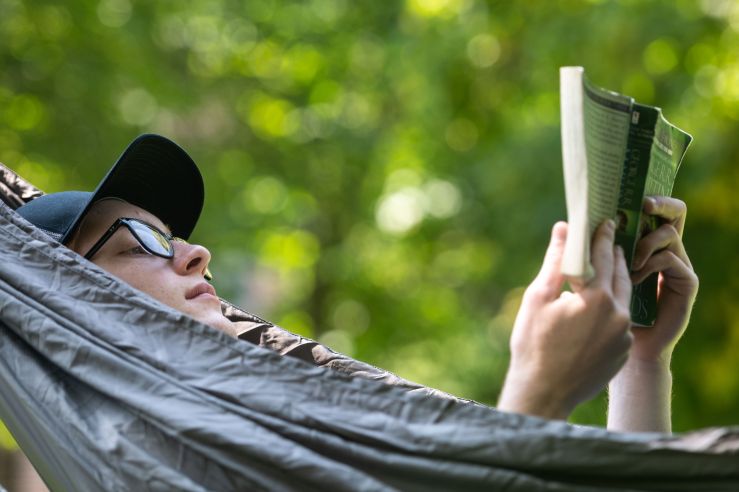 Photo of person reading in a hammock on campus