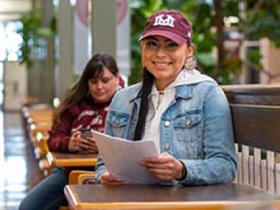 Student smiling while wearing UM hat