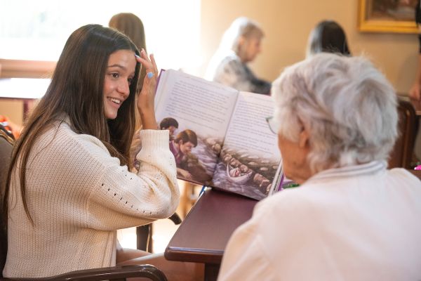 A student reads to an elderly community member