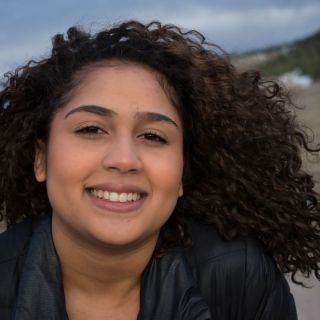 Woman with curly brown hair at the top of mountain. 