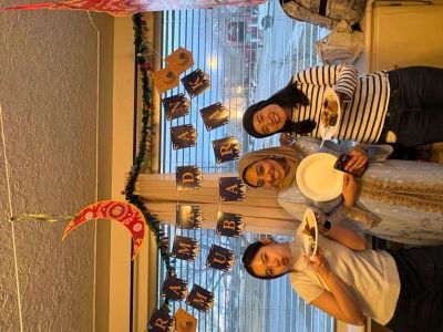 3 Students posing for a photo under a "Ramadan Mubarak" banner