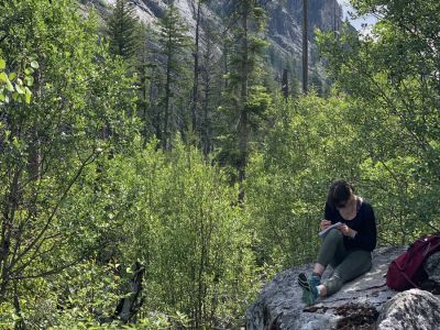 Schwanke participant sitting on a rock and writing.