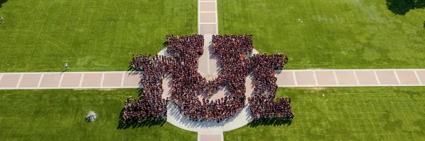 A drone shot of new students standing on the Oval in the shape of UM.