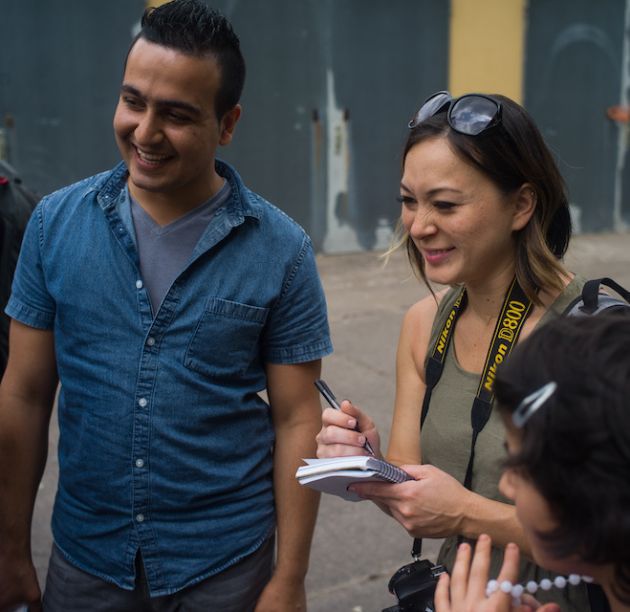 Woman with notebook in hand laughs with others.