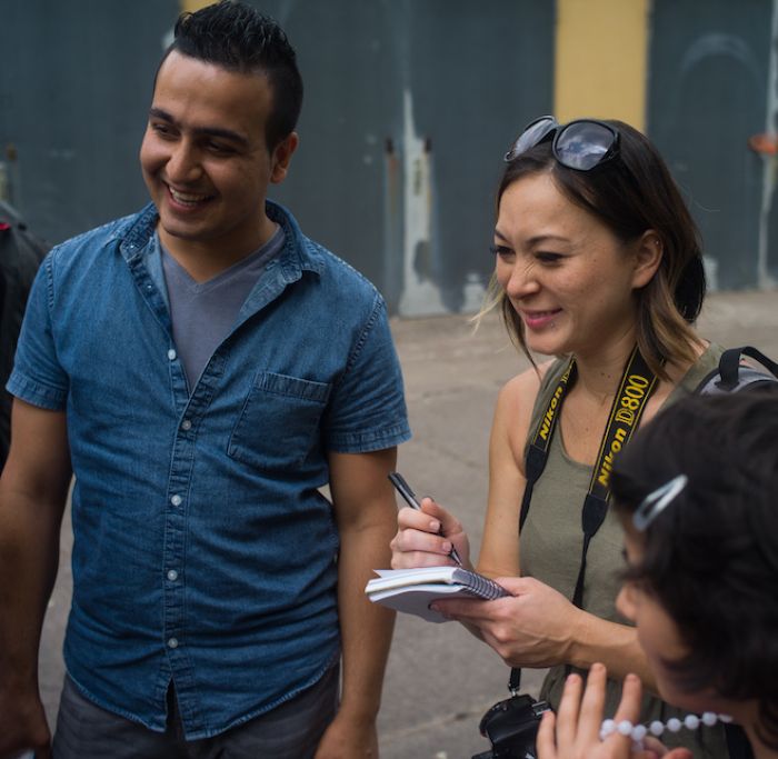 Woman with notebook in hand laughs with others.