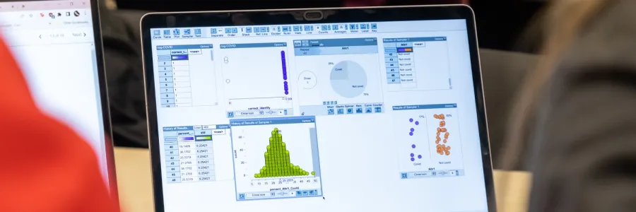 A laptop on a table showing data model graphs on the screen.
