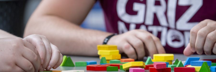 close up of the hands of several people playing with toy blocks