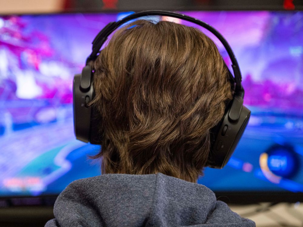 A student wearing headphones games on a computer