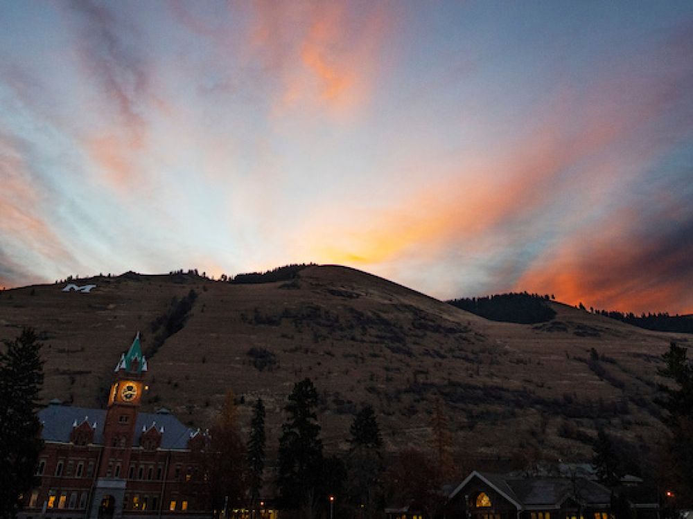 The sun rises behind Mount Sentinel and Main Hall