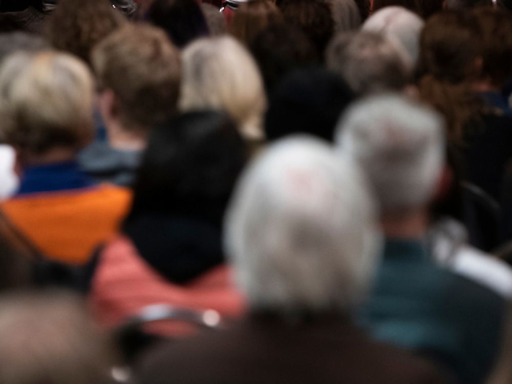 looking toward a stage from behind a seated audience 