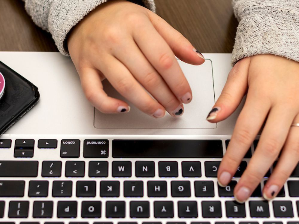 student works on laptop with cell phone nearby