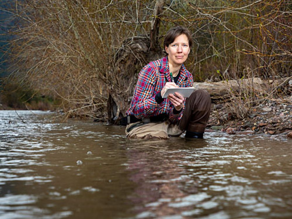 A picture of Claire Rawlings Gilder kneeling in a river with waders