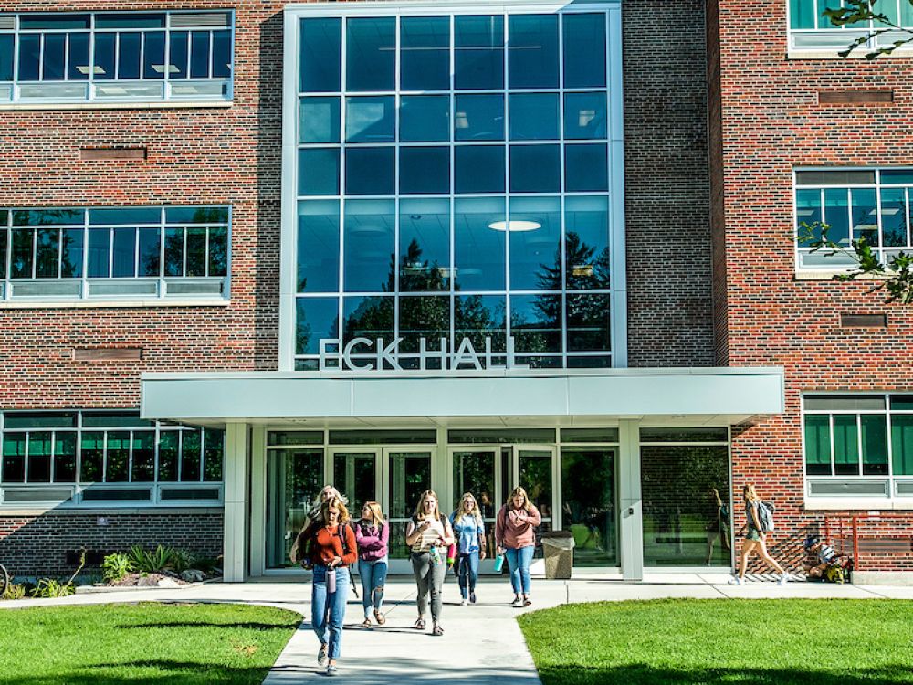 Students walk out of Eck Hall on a sunny day