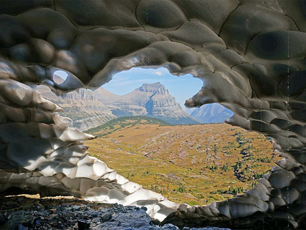 A view of Going-to-the-Sun Mountain through melting snow and ice at the origin of Reynolds Creek near Logan Pass in Glacier National Park, Montana.