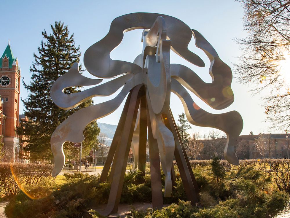 Students walk past welded steel sculpture titled “Teepee Burner" with Main Hall in the background