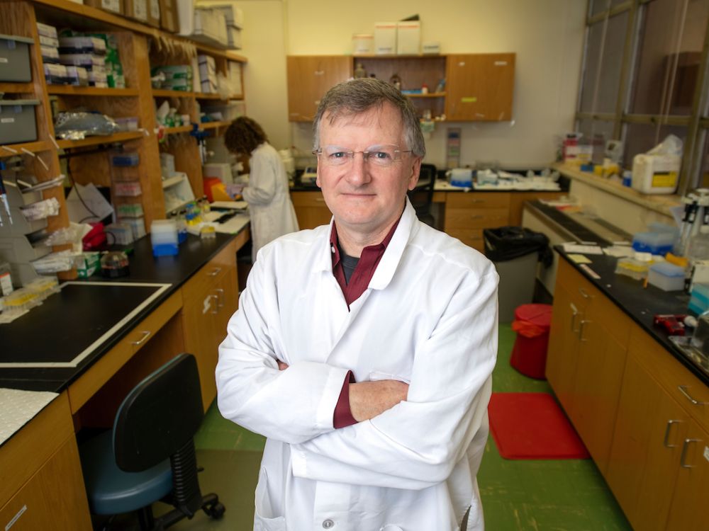 Jay Evans stands in a white lab coat in a lab 