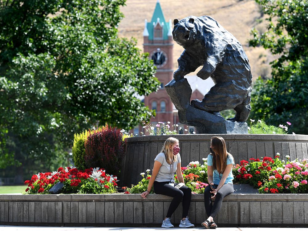 Students with masks chat by the Grizzly Bear statue.