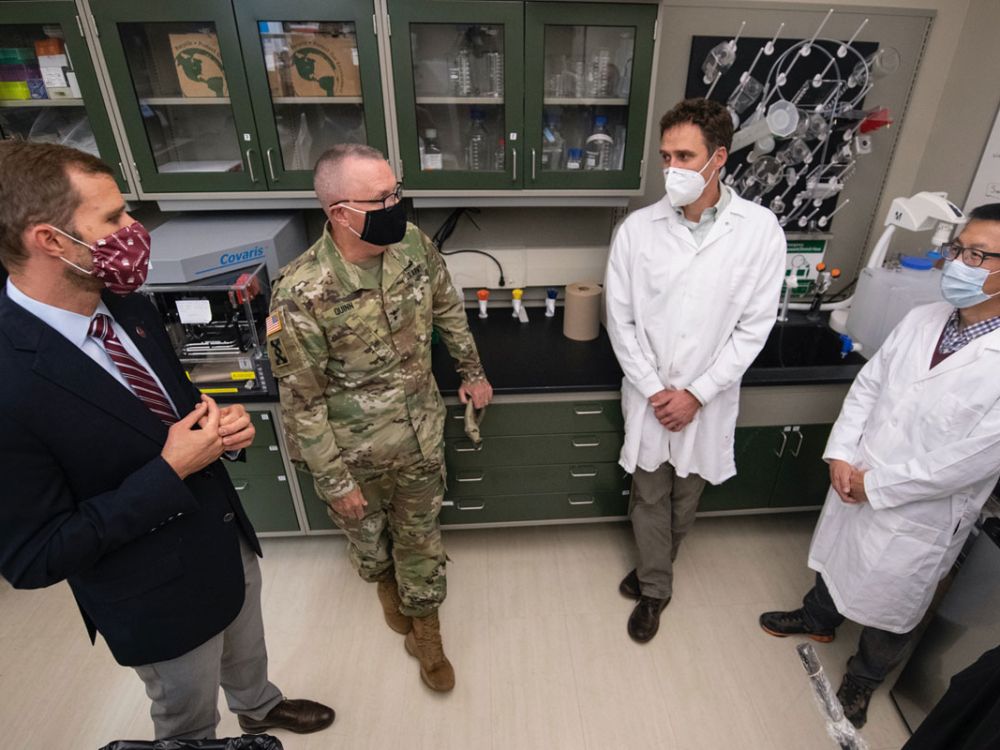 Four government officials speak in a UM lab.