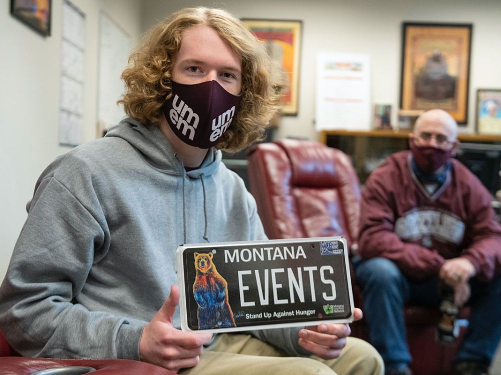 UM student Jack Person holds a license plate that says "Montana Events." 