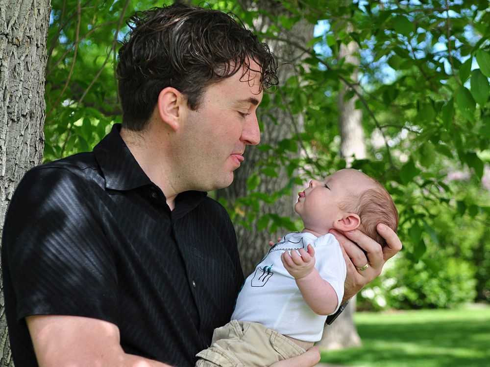 A dad sticks his tongue out at a newborn baby.
