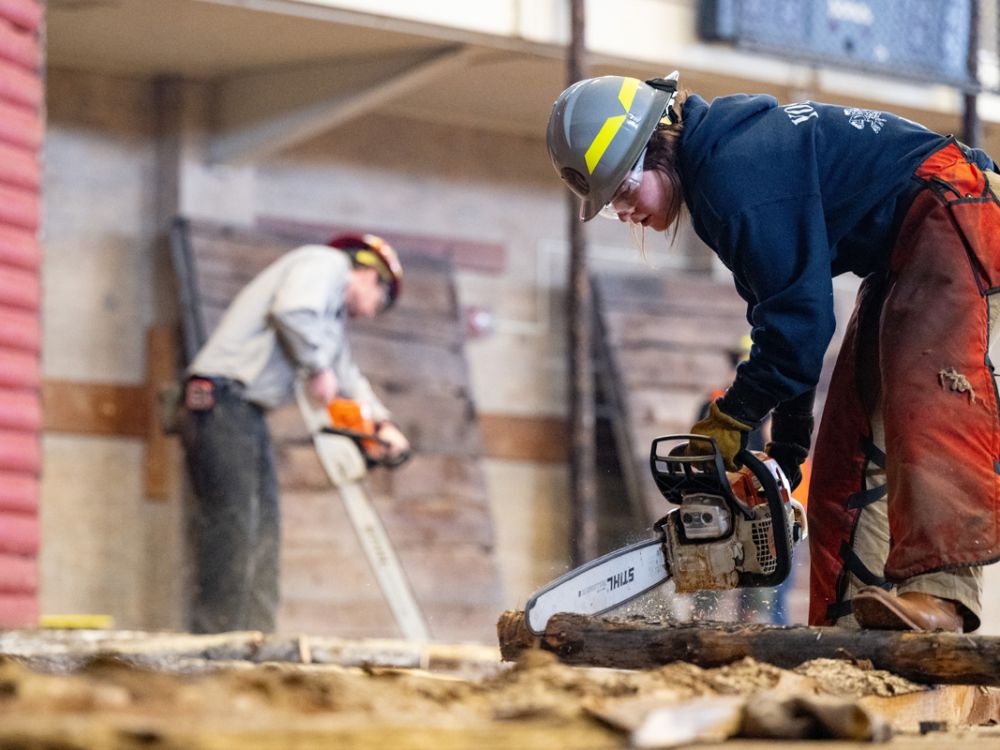 A photo of a forestry student using a chainsaw to build the Foresters' Ball.