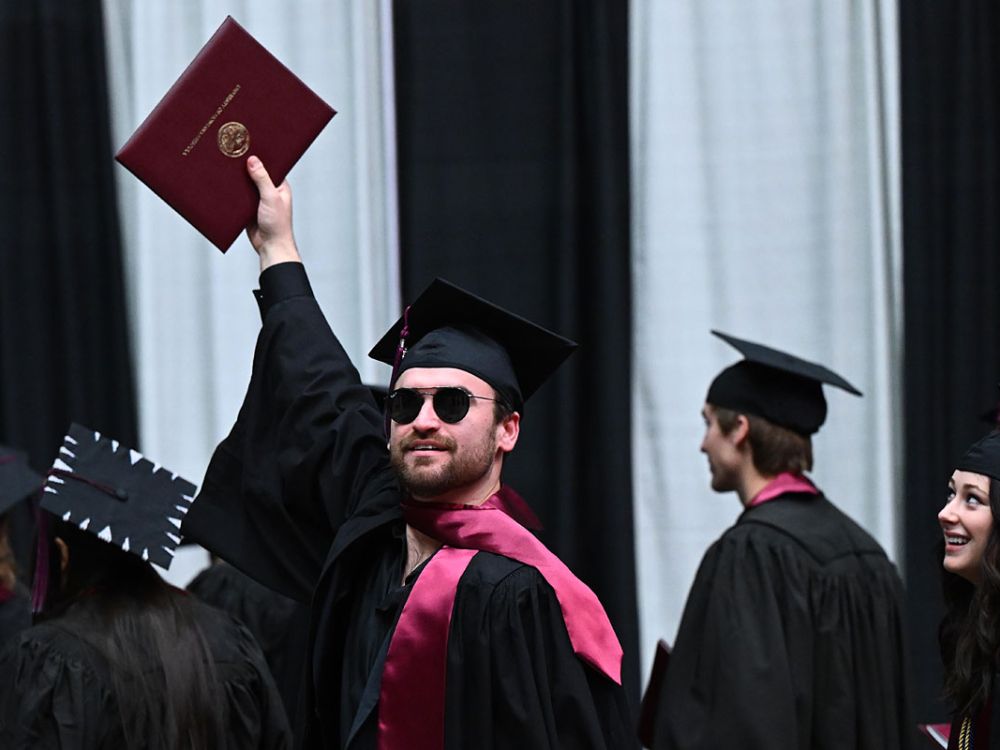 A student holds aloft his diploma at a recent UM graduation ceremony.