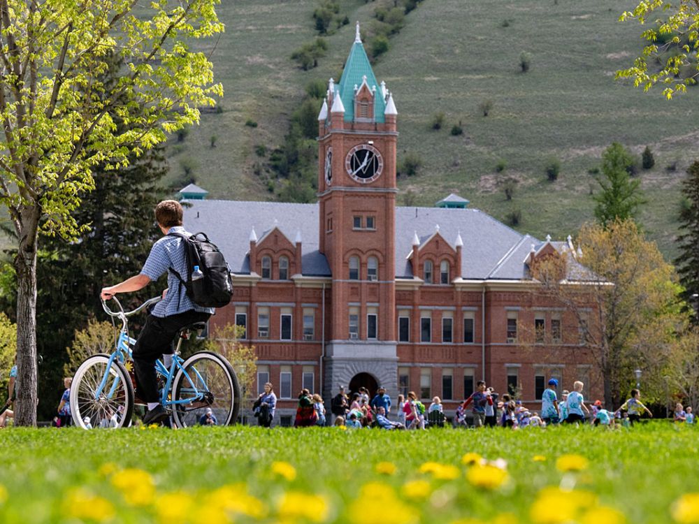 A biker travels across the Oval before Main Hall on the UM campus.