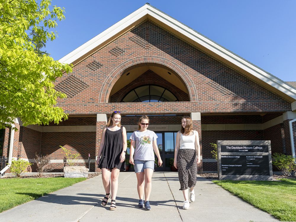 Students walk before the Davidson Honors College at UM.