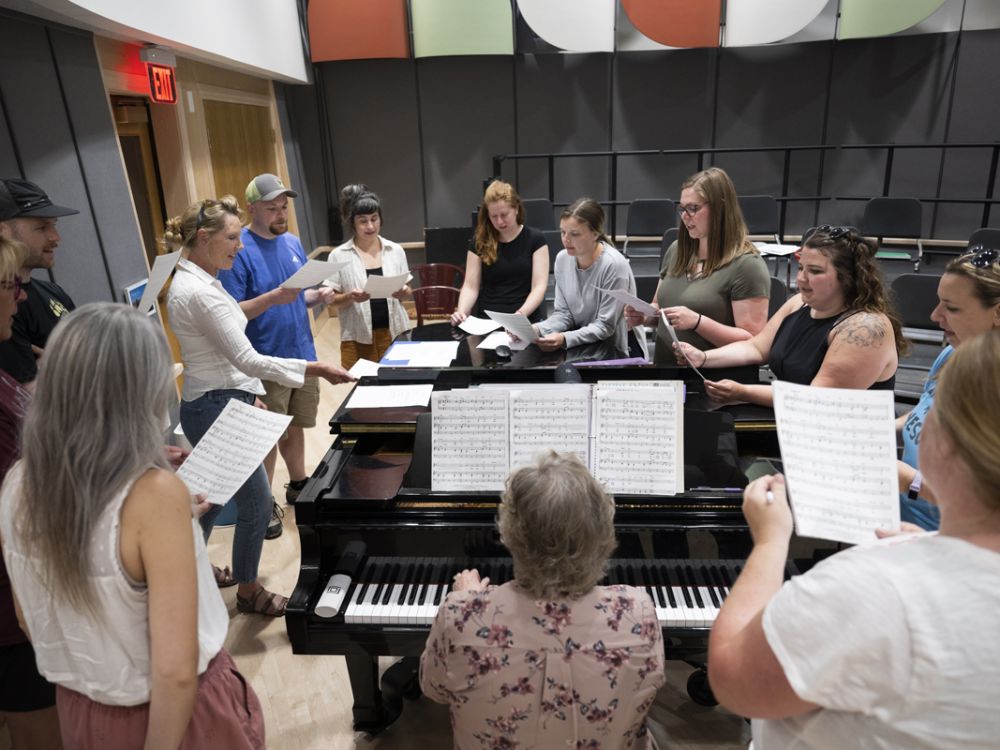 UM students gather around a piano while singing. 