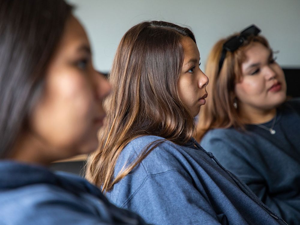 Three young Native women listen in a class.
