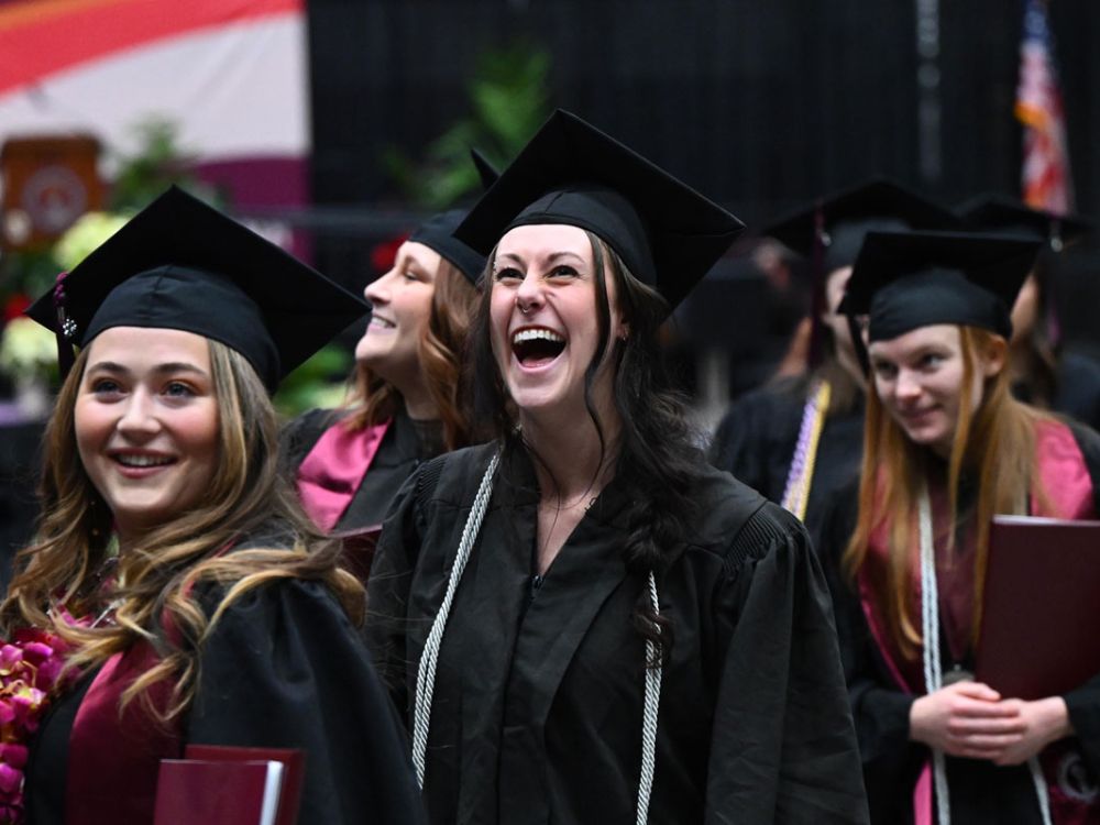 Three students smile at UM fall graduation.