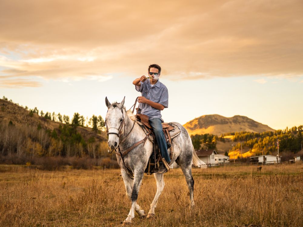 An image of a teenager riding a horse while smudging sage. 