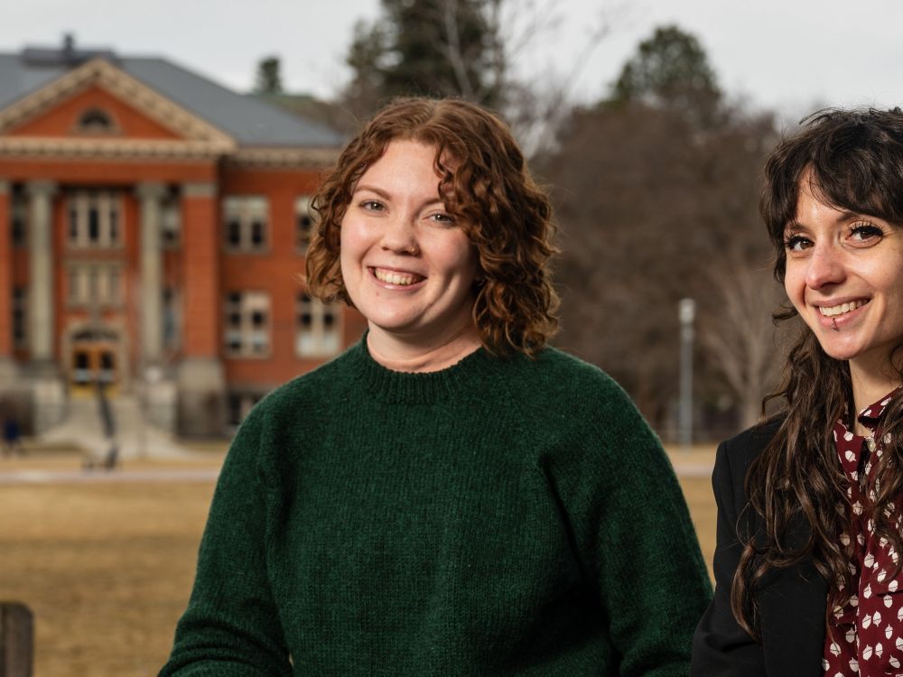 Two UM students sit on campus. 