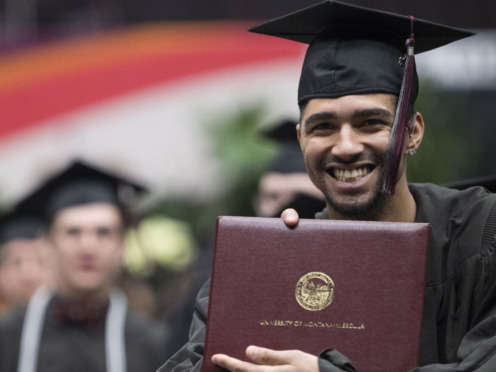 A UM student holds his diploma at Commencement.