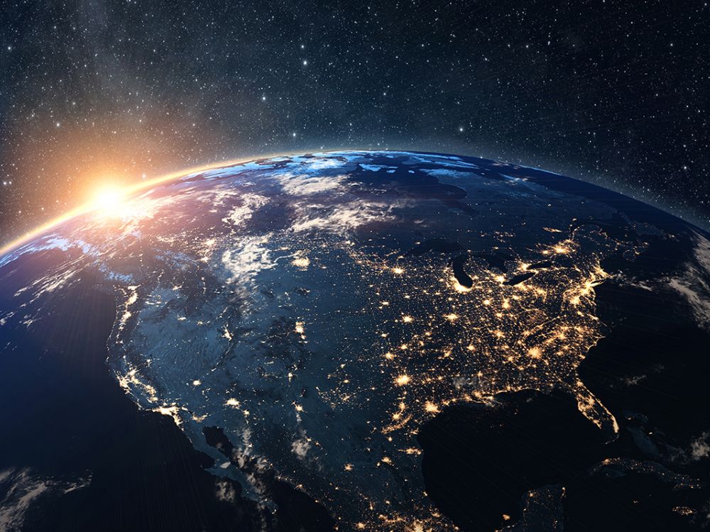 A picture of the Earth from orbit at night with glowing lights.