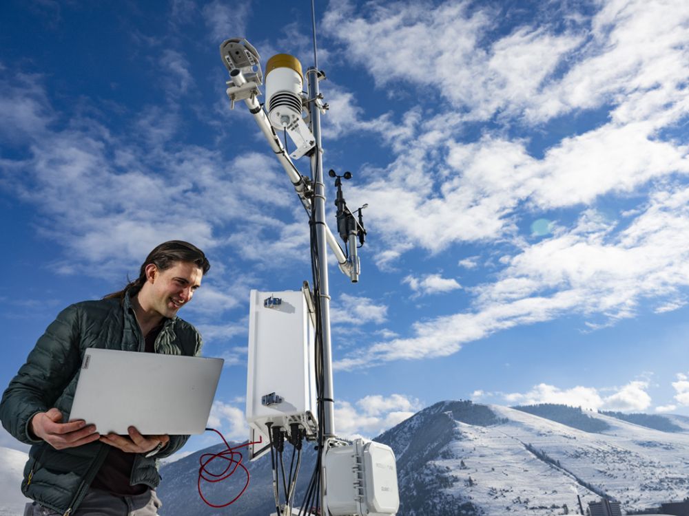 A photo of UM junior Joseph Knudsen standing on top of the Missoula Public Library with the HART Station. 