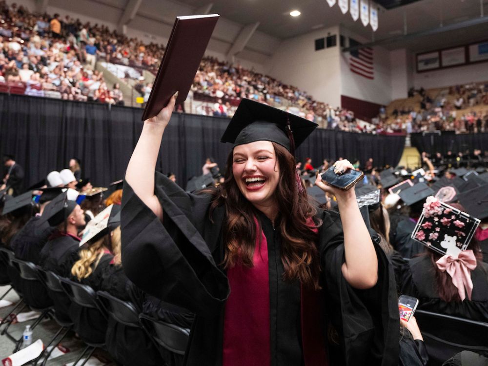 A UM graduate celebrates after receiving her diploma.