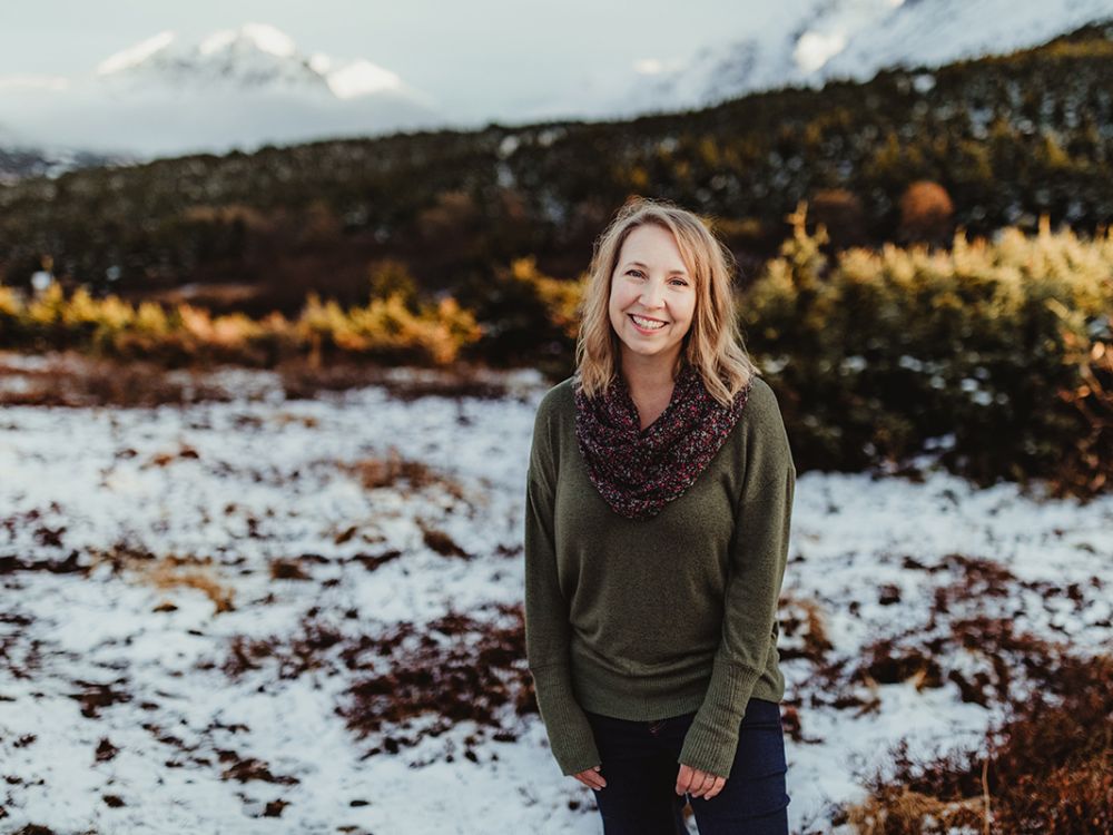 A picture of Heather Johnson standing in a snowy landscape with mountains behind her.