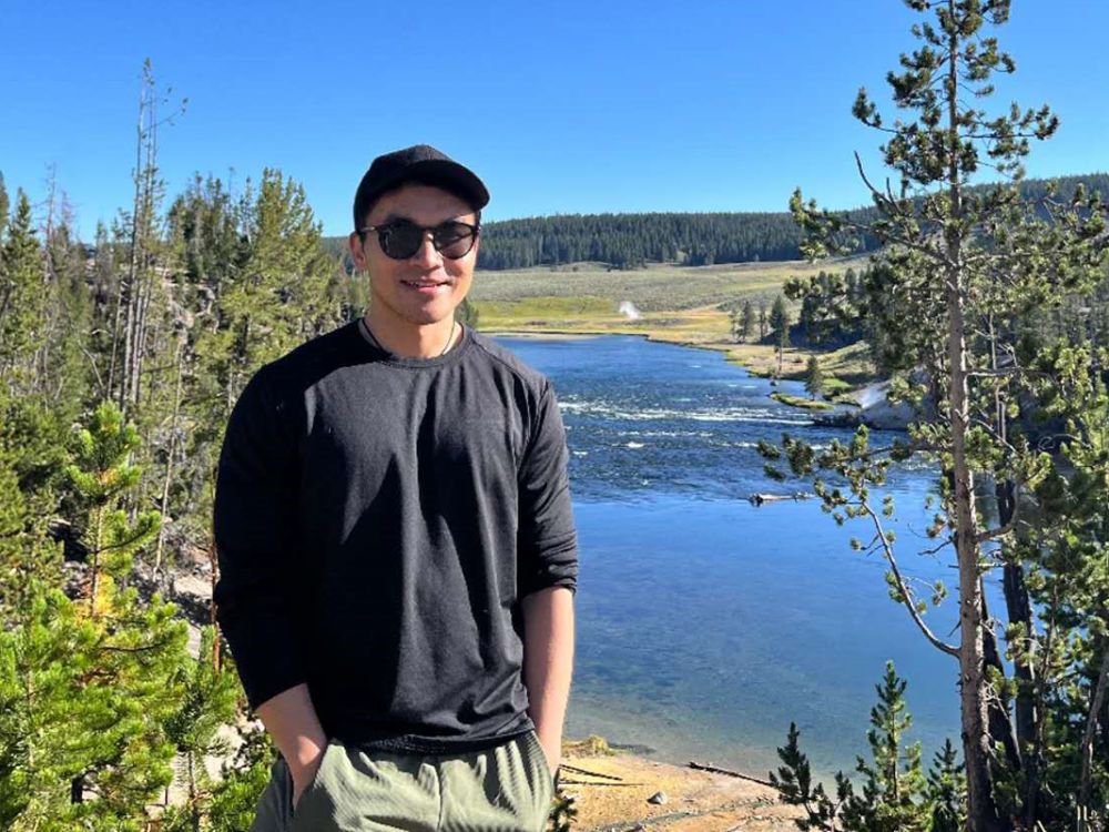 A picture of Lixu Hu standing with a river behind him in Yellowstone National Park.