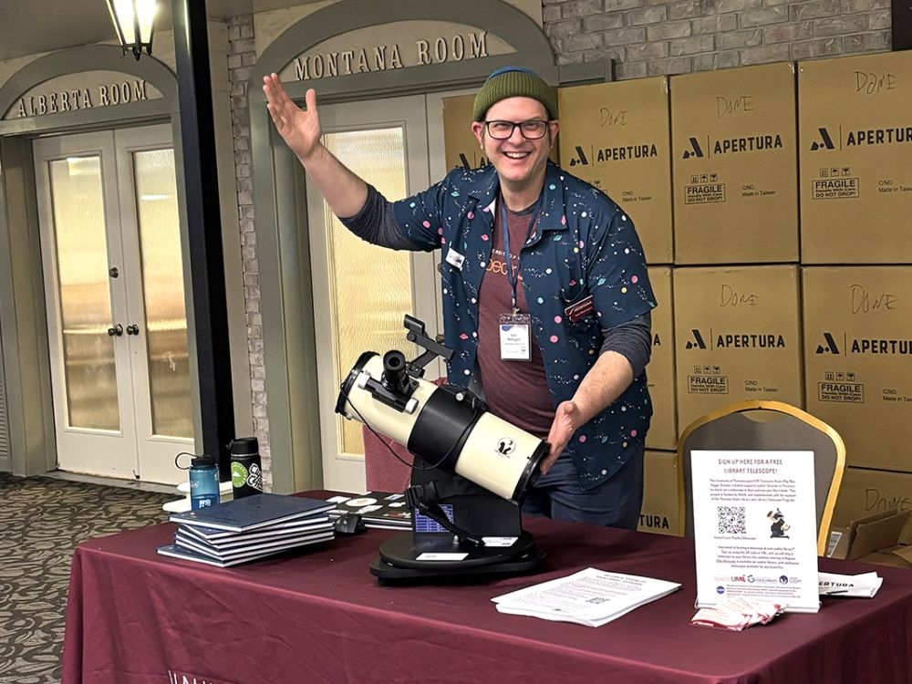 A picture of Nick Wethington displaying a telescope at a tabling event.