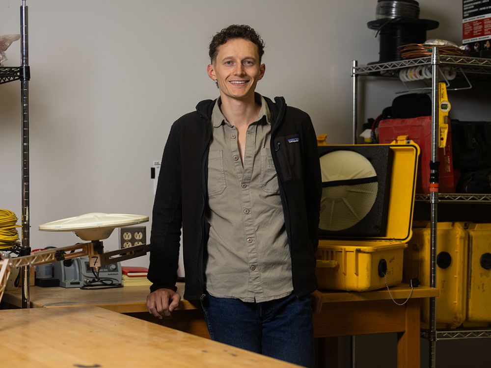 A picture of Matthew Swarr with some science equipment behind him.