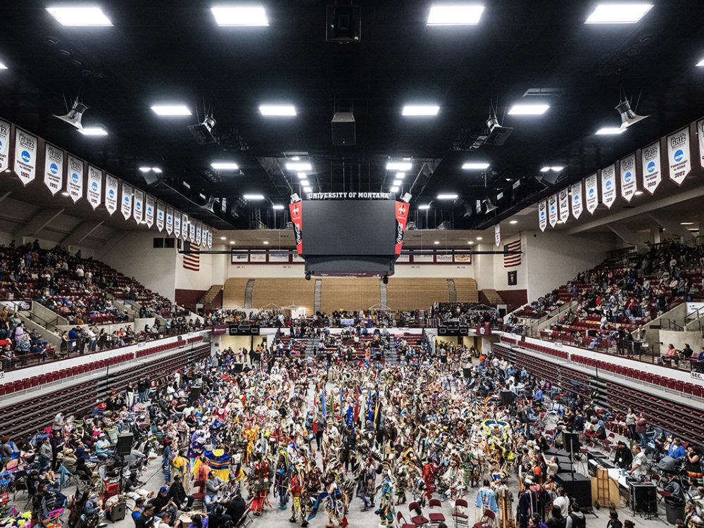 Indigenous dancers fill the floor of the Adams Center for the powwow