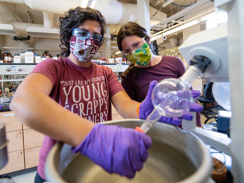 Two UM students work in a lab while wearing masks