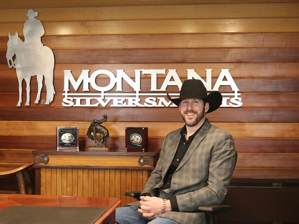Lance Neirby sits at a desk with a cowboy hat on.
