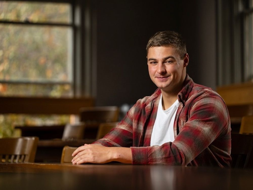 Kolter Stevenson, a UM student, sits next to a tree on the UM campus.