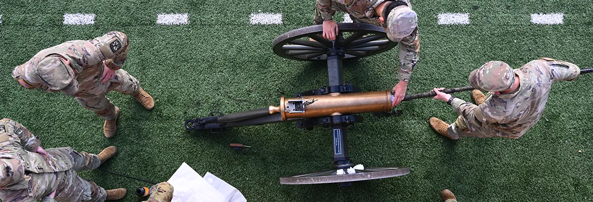 An aerial view of the UM ROTC Boom Crew members in uniform loading the cannon at a football game in Washington-Grizzly Stadium in Missoula, Montana.