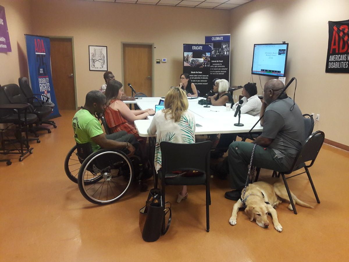 Group of people sitting around a table, some with laptops open.