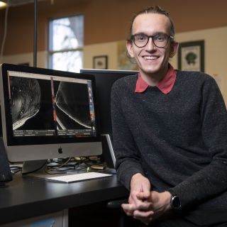 UM senior Devin Hunt turns away from a desktop computer and smiles at the camera