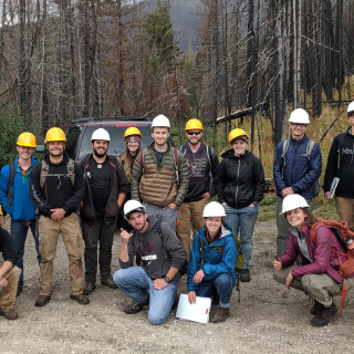 Class of students poses outside wearing hard hats